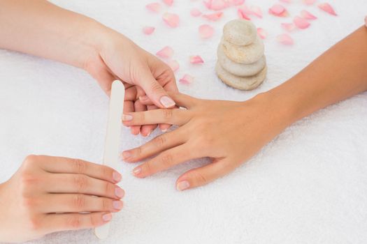 Close up of beautician filing female client's nails at spa beauty salon