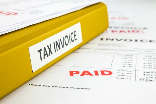 Binder of tax invoice documents with bills, business receipts and payment of invoices, focus on word paid