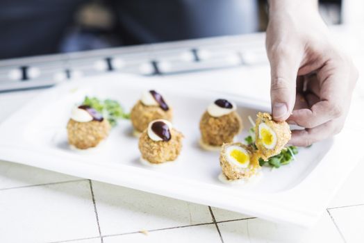 scotch breaded eggs  contemporary fusion style being served in gourmet restaurant
