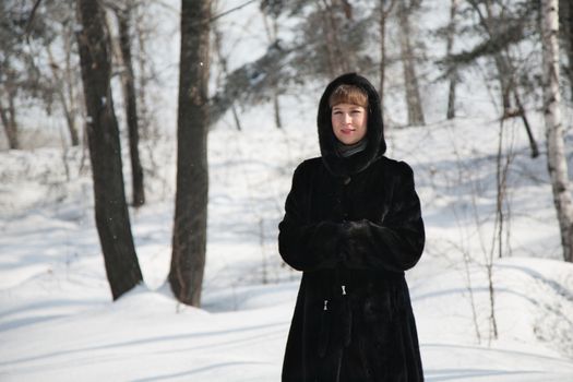 girl in winter forest in a black fur coat