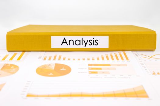 Yellow document binder with analysis word place on graphs, charts and business reports