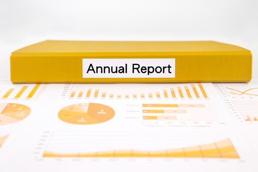 Yellow binder with annual report word place on graphs, charts and project evaluation document