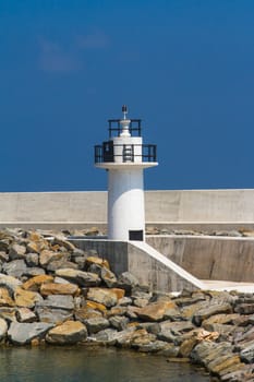 View of white lighthouse on clear, blue sky.