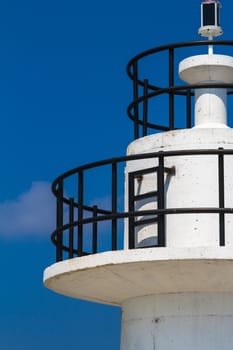 Close up view of white lighthouse on clear, blue sky.