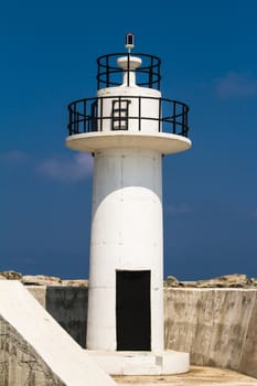 Close up view of white lighthouse on clear, blue sky.