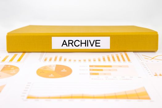 Yellow document binder with archive word place on data record, graph analysis and business reports