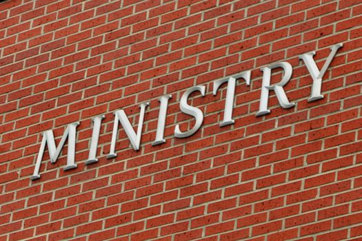 Religious image with the word "ministry" on a brick wall.