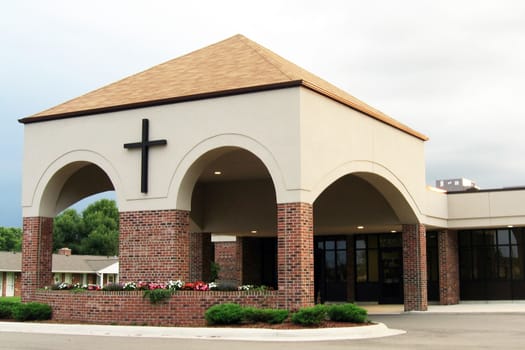 Modern church entrance with a cross on the building.