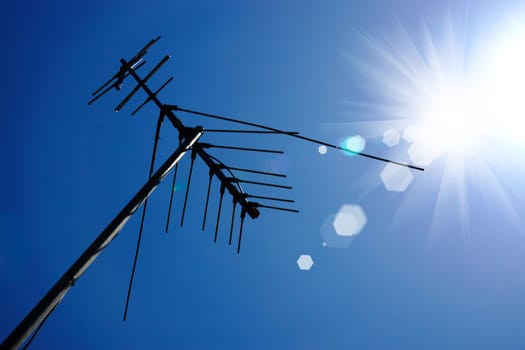 Silhouettes of Television antenna with sky background and sun.