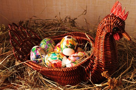 Decorative wicker vase in the form of chicken with Easter eggs inside, placed on lacy napkin