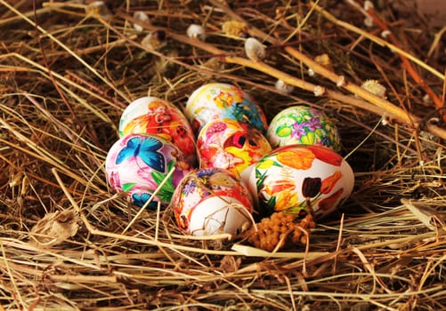 Decorative wicker vase in the form of chicken with easter eggs, placed on the hay