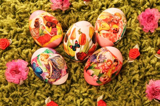 Easter eggs with pictures of flowers and butterflies placed on a green synthetic  grass