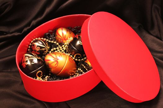 Decorative Easter eggs in a red gift box placed on a black silk