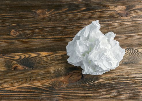 crumpled white paper on a brown wooden background