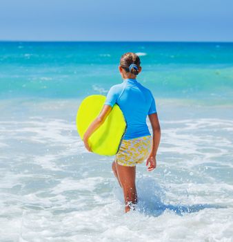 Back view of Teenage girl in blue has fun surfing