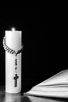 Candle with wood cross and bible on table