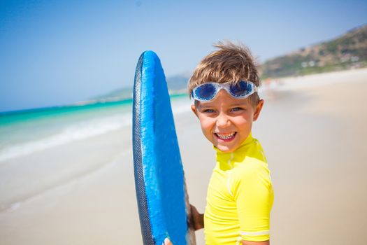 Portrait of little boy in yellow has fun surfing