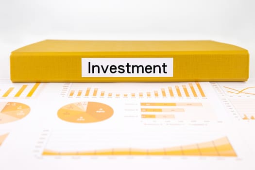 Yellow document binder with investment word place on income summary, graph analysis and financial report for budget plan
