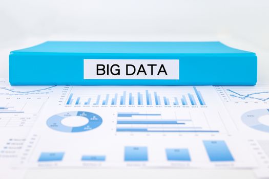 Blue document binder with big data word place on graphs, charts and research reports