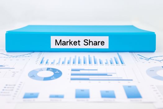 Blue document binder with Market Share word place on graph analysis, charts and Marketing reports