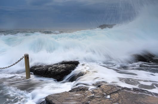Bracing for the large powerful waves crashing over the rocks at Blowhole Point Rock Pool