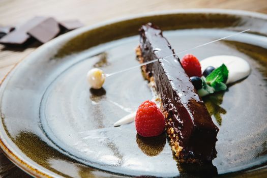 Piece of chocolate cake with  fresh berry on wooden background