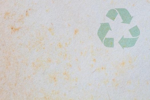 texture of old paper with yellow stain, background, with symbol of recycle on the upper corner
