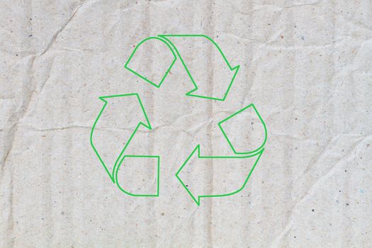 background of crumpled grey cardboard with texture, with green sign of recycle