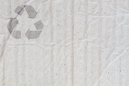 background of crumpled grey cardboard with texture, with symbol of recycle on the upper corner