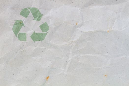 crumpled grey cardboard with background and texture, with symbol of recycle on the upper corner