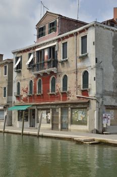 Facade of building in disrepair on  a canal in Murano, an island in the Venetian Lagoon, northern Italy.
