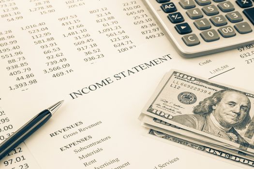 Dollar money place on business income statement with detail list of revenues and expenses, accounting reports on background, sepia tone image