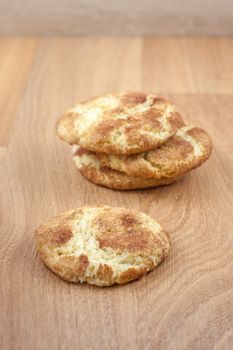 A stack of snicker doodles on a wooden surface.