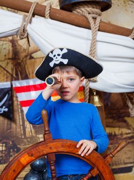 Cute little boy wearing pirate costume on the deck of a ship