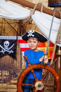 Cute little boy wearing pirate costume on the deck of a ship