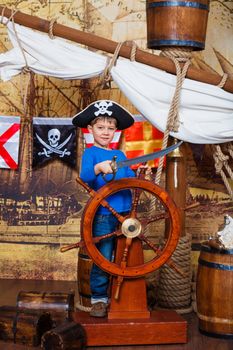 Cute little boy wearing pirate costume on the deck of a ship