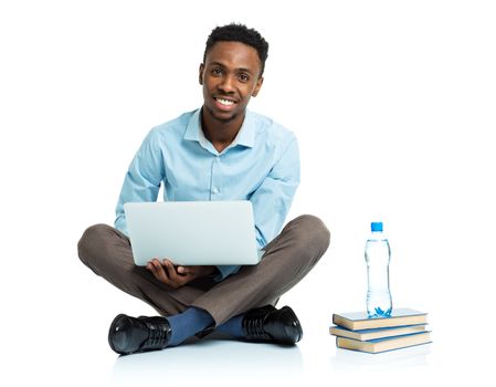 Happy african american college student with laptop, books and bottle of water sitting on white background