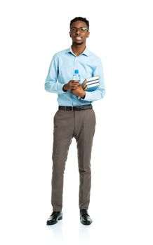 Happy african american college student with books and bottle of water in his hands  standing on white background