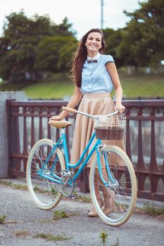 Young beautiful, elegantly dressed woman with bicycle. Beauty, fashion and lifestyle