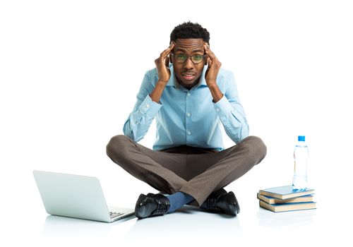 Happy african american college student with laptop, books and bottle of water in stress sitting on white background