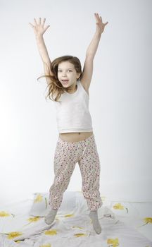 Little girl jumping on bed isolated on white