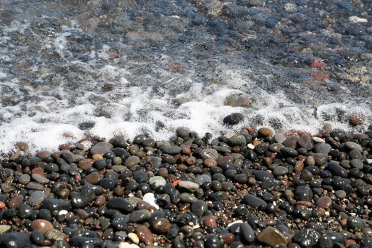 The Kamari beach with black volcanic stones at Santorini island, Greece