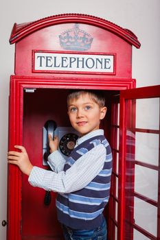 Cute little boy in the red telephone box