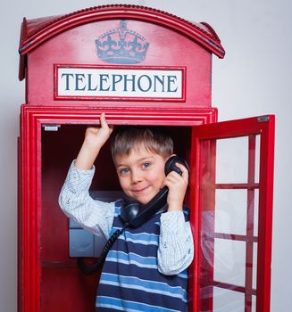 Cute little boy in the red telephone box