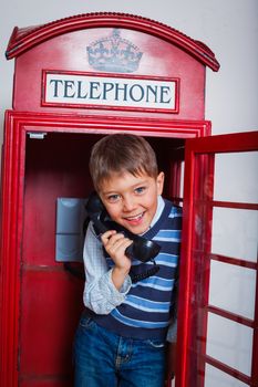 Cute little boy in the red telephone box