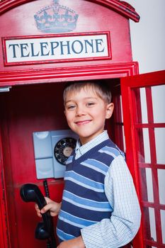 Cute little boy in the red telephone box