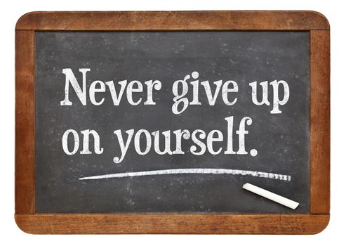 Never give up on yourself - motivational advice on a vintage slate blackboard