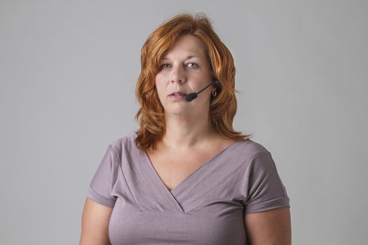 forty years old woman with red hair with headset with an empty look