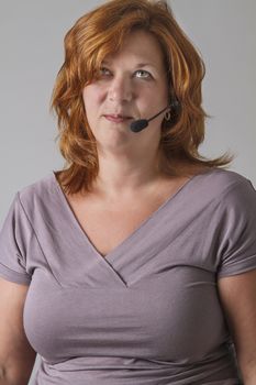 forty year old woman with red hair with headset looking up in annoyance