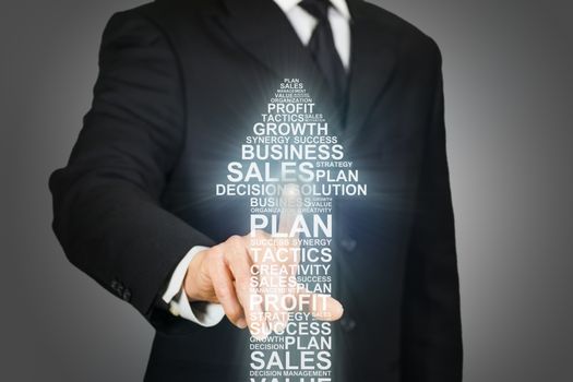 Businessman clicking on an upward arrow formed by business related words